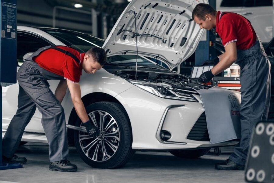 Two technicians inspecting a white car