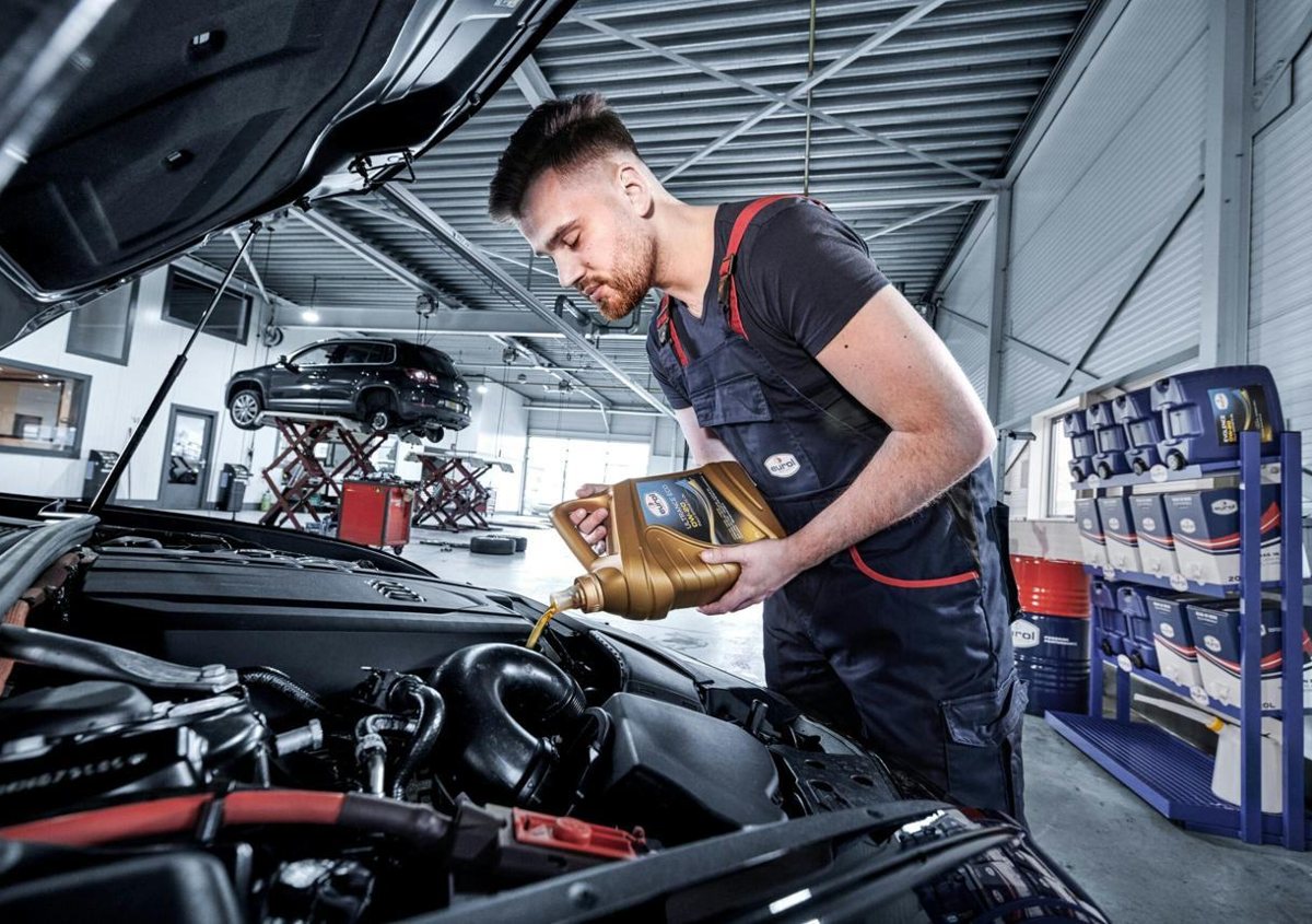 Technician topping up engine oil under the hood