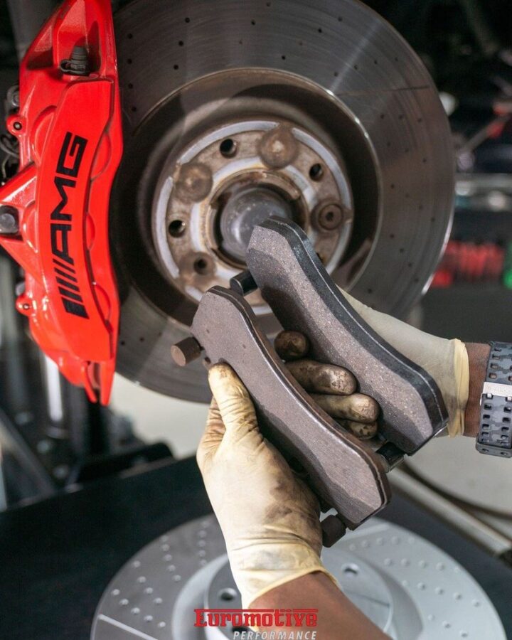Technician holding a brake pad in front of a brake disc