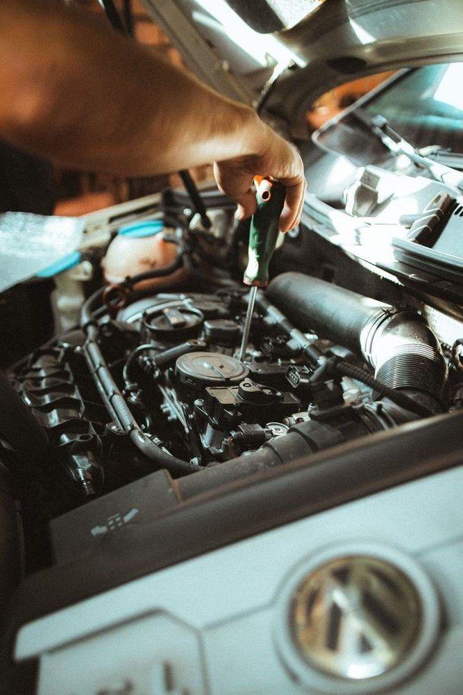 Technician inspecting an engine bay with a screwdriver