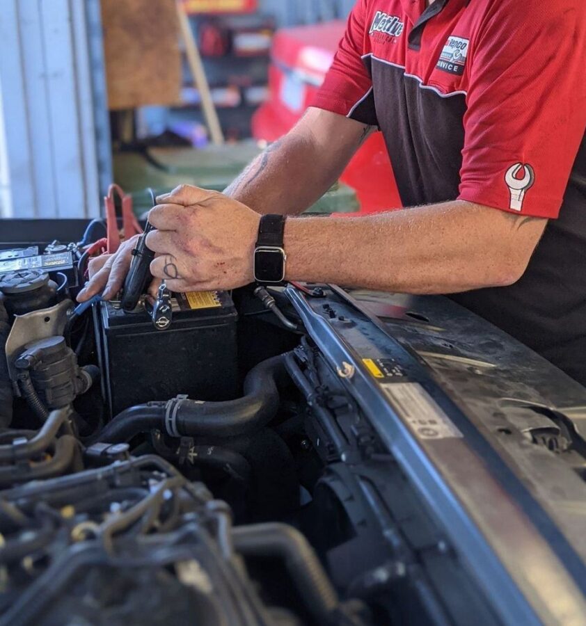 Technician testing a car battery under the hood